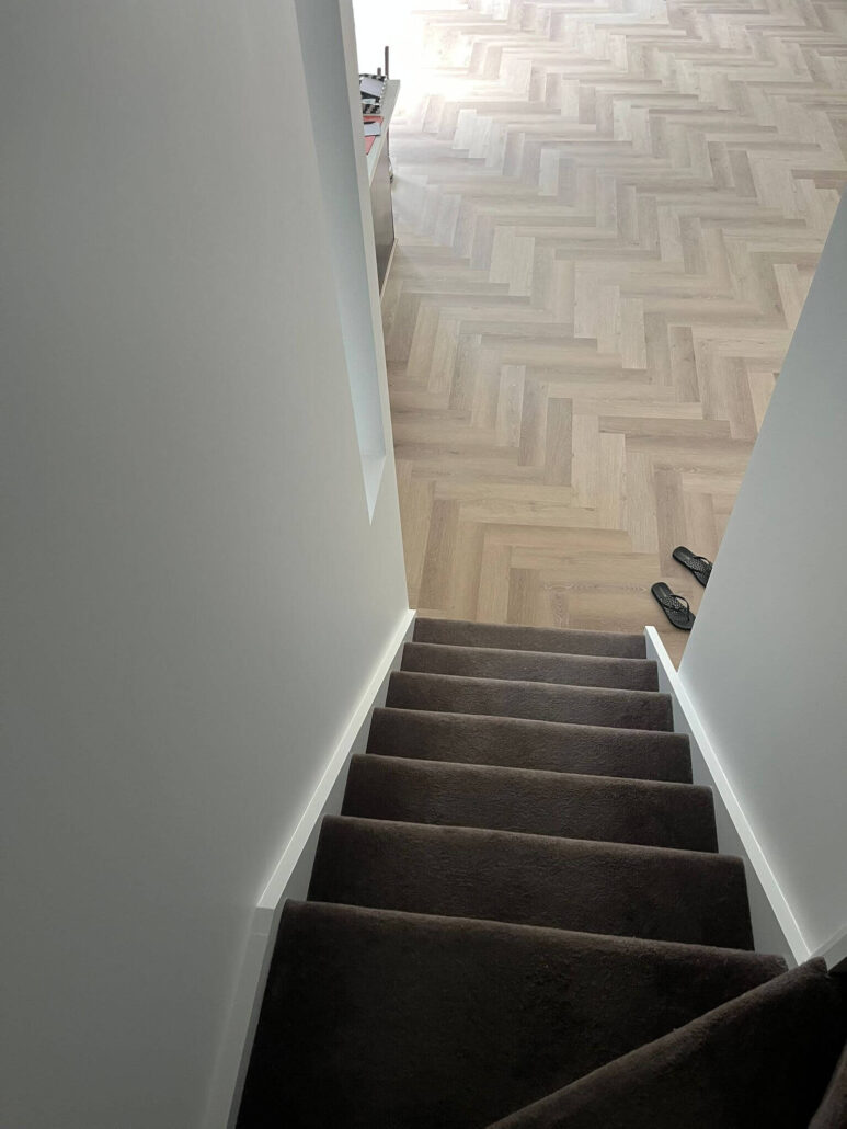 Staircase area painting and herringbone hybrid flooring detail in Altona residence