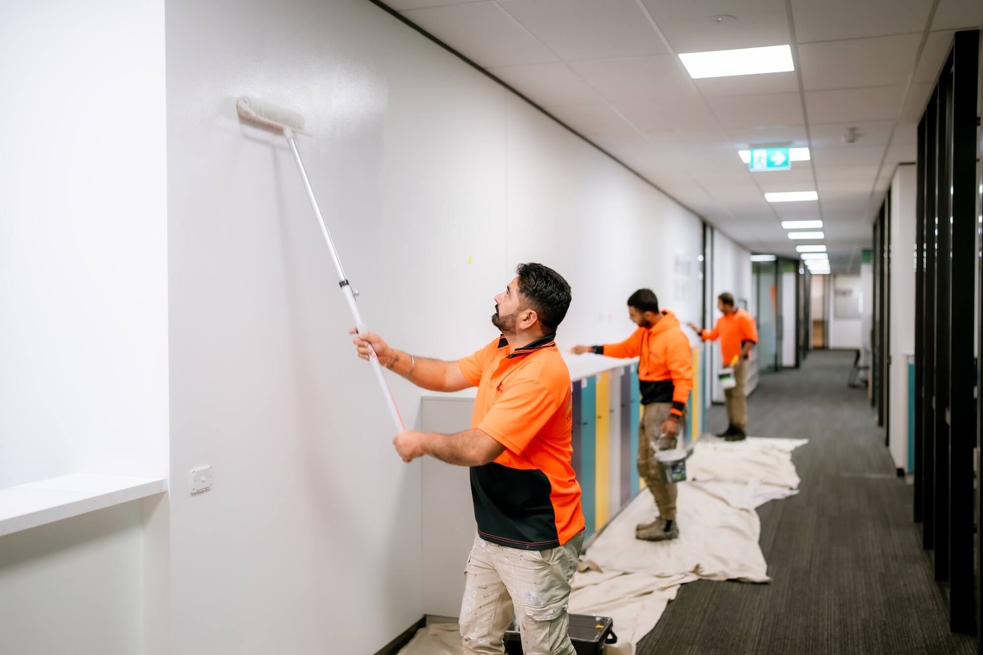 Painter applying paint to an office wall during a commercial painting project